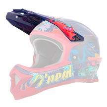 Der O'NEAL Visor SONUS Youth Helmet REX ist ein farbenfroher Motocross-Helm mit farbenfrohen Grafiken mit einem T-Rex, Palmen und einem grünen Van. Die vorherrschenden Farben sind Rot, Blau und Neontöne, wobei das Design seitlich den Markennamen „O'NEAL“ zeigt.