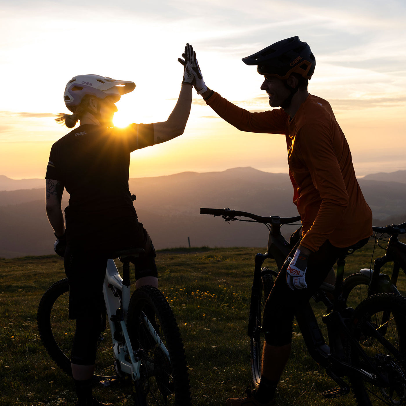 Zwei Mountainbiker geben sich bei Sonnenuntergang ein High-Five